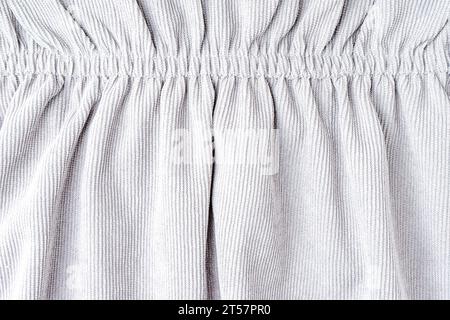 White corduroy fabric gathered with elastic close-up. Velveteen texture with folds and drapery. Cloth surface, textile background, wallpaper, backdrop Stock Photo