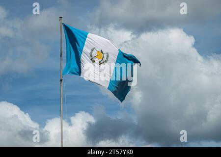 Guatemala, La Antigua - July 20, 2023: Closeup of national flag waving in wind against blue cloudscape Stock Photo