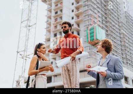 Corporate architects discussing a new project outdoors, reviewing blueprints and strategizing design. Stock Photo