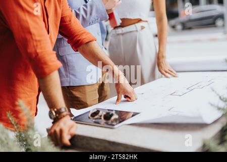Architectural team discusses blueprint, plans, and costs. Collaboration between engineers, designers, and contractors for an innovative project. Stock Photo
