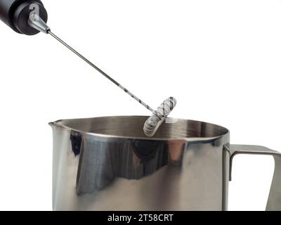 Automatic milk foam maker. Metal milk mug and electric milk frother isolated on a white background. Stock Photo