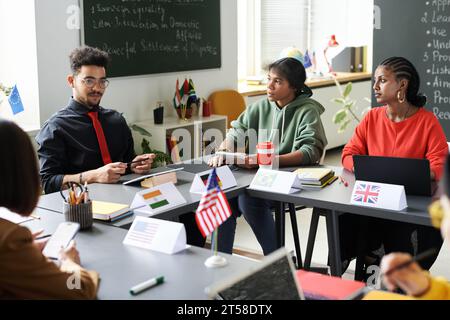 Group of students sitting at seminar together with teacher and working in team in the classroom Stock Photo