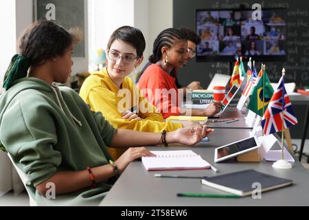 Group of international students having conference in the classroom, they sitting at table and using gadgets Stock Photo