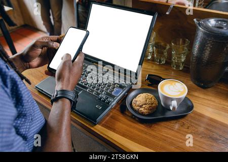 top view of unrecognizable black businessman using his phone sending messages and checking financial earnings, while working on his online business wi Stock Photo