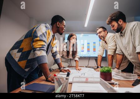 Multiracial architects and engineers collaborate in a corporate boardroom, discussing blueprints, brainstorming ideas. Stock Photo