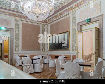Reception hall at La Fenice theater in Venice, Italy. Chairs wrapped in fabric surround the tables. Stock Photo