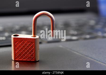 Open padlock with red light reflection indicating security alert on computer keyboard background Stock Photo