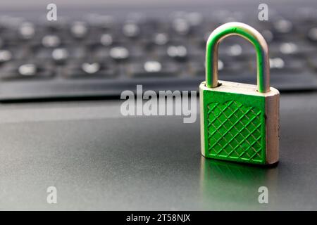 Closed padlock with green light reflection indicating security on computer keyboard background Stock Photo