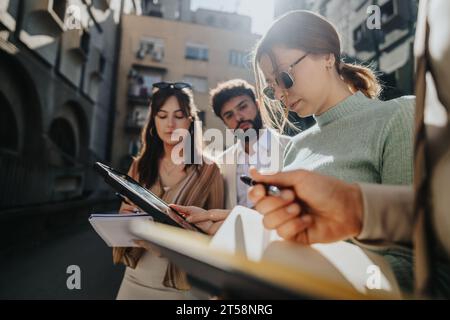 Young professionals collaborate outdoors discussing market trends, analyzing competition, and brainstorming business expansion ideas. Stock Photo