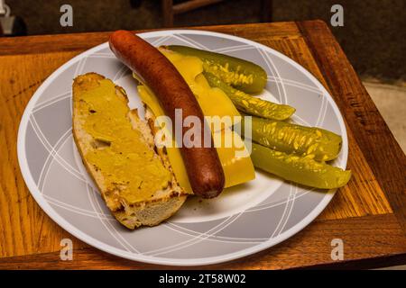 A sandwich with a French baguette and dijon mustard , Norwegian Jarlsberg cheese, Polish hotdog, and American Dill pickle on the side. Stock Photo