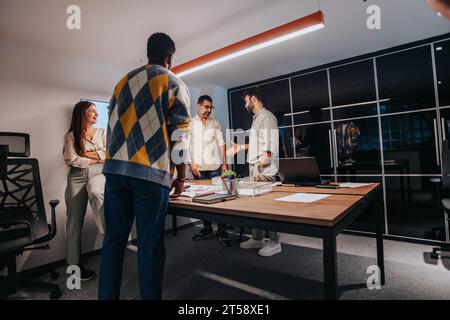 Multiracial Team of Architects and Engineers Collaborating on Architectural Blueprint in Board Room Stock Photo