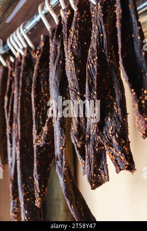 Freshly made biltong hangs from hooks on a rack in a small shop in South Africa Stock Photo