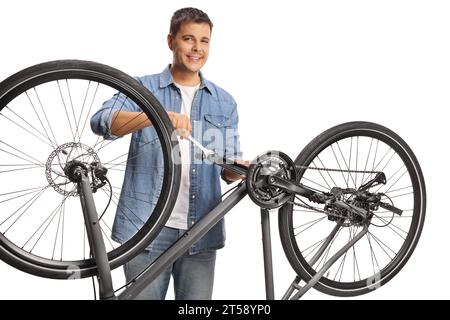 Young man fixing a bicycle with a pedal wrench isolated on white background Stock Photo