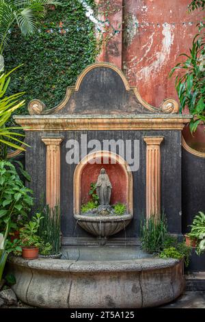 Guatemala, La Antigua - July 20, 2023: Virgin Mary fountain at shopping mall on east side of Plaza Mayor, central square. Small statue set in niche be Stock Photo