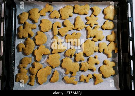 Freshly baked Christmas cookies lie on baking paper on a baking sheet. Top view Stock Photo