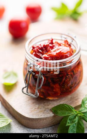 Jar with homemade sun dried tomatoes with fresh herbs and spices. Stock Photo