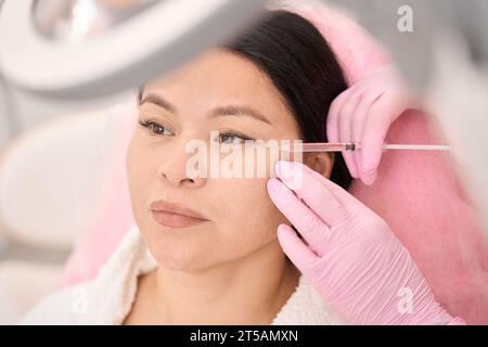 Asian woman receiving beauty injections in a cosmetology clinic Stock Photo