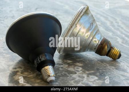 New plastic 15W LED and 20 year old metal and glass 120W outdoor security spotlight bulbs. PAR38 fittings for motion detector device. Australia, Stock Photo