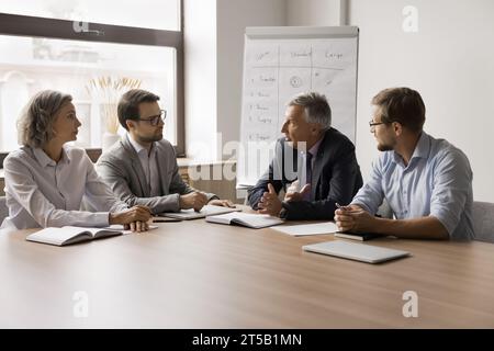 Serious older businessman speaking to business partners Stock Photo
