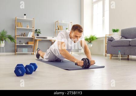 Sporty athletic man exercising at home on the floor. Fitness and home training concept. Stock Photo
