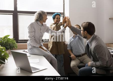 Happy positive diverse team of managers giving group high five Stock Photo
