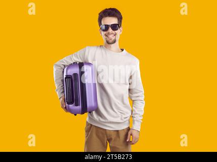 Happy tourist man in sunglasses holding modern suitcase Stock Photo