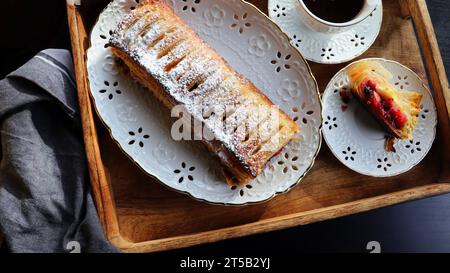 Traditional freshly baked whole apple strudel on wooden table, close up. Fresh homemade pastries with fruit or berry filling . Stock Photo