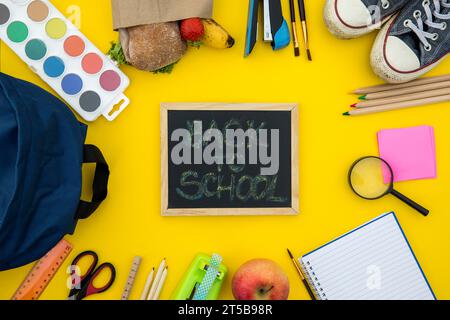 Blackboard with school accessories yellow background Stock Photo