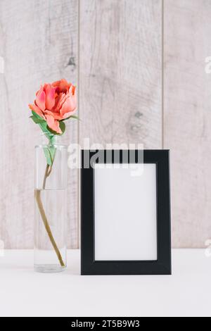 Colorful flower vase near blank picture frame table Stock Photo