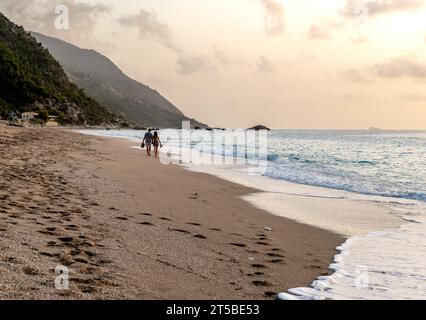 A couple on holiday walking on a beautiful long sandy beach. Stock Photo