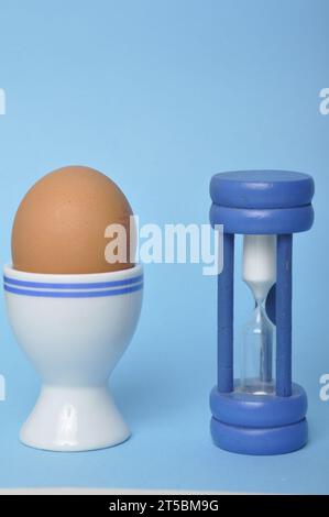 Boiled egg and hourglass on a blue background Stock Photo