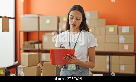 African american woman ecommerce business worker writing on document checking pacakges at office Stock Photo