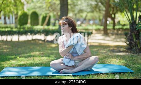 Middle age beautiful sportswoman wearing sportswear sitting on mat