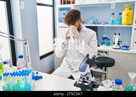 Young arab man scientist using napkin at laboratory Stock Photo