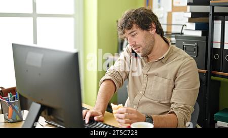 Young hispanic man business worker having breakfast working at office Stock Photo