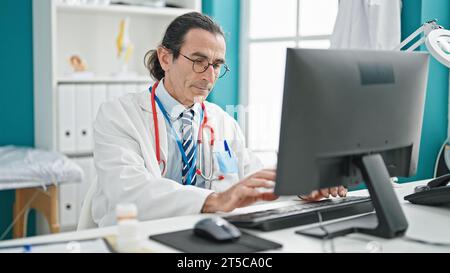 Middle age man doctor using computer at the clinic Stock Photo