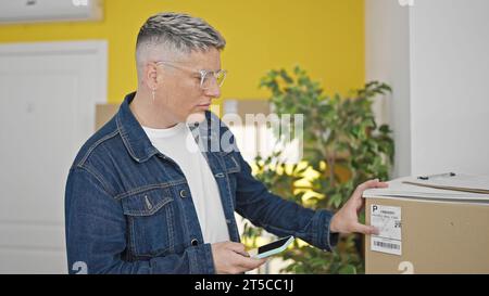 Young caucasian man ecommerce business worker using smartphone reading package label at office Stock Photo