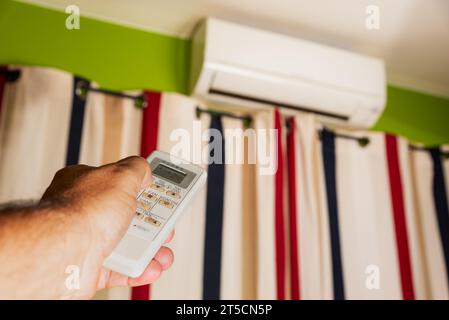 Man's hand grabbing and manipulating the remote control of the home air conditioner. Stock Photo