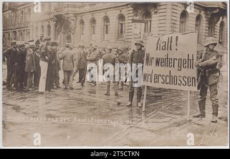 'Strassenszene aus den Revolutionstagen Berlins' / 'Street scene from the revolutionary days of Berlin': Roadblock or military checkpoint on the streets of Berlin during the German Revolution of 1918-1919, after the First World War. Two uniformed soldiers are holding a large notice that says 'Halt! Wer weitergeht wird erschossen' / 'Stop! Anyone who continues will be shot'. Other soldiers are in the background, stopping a group of men (including a sailor) from going past Stock Photo