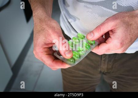 Man holding a blister pack of green capsules. Medicine, health care concept. Stock Photo