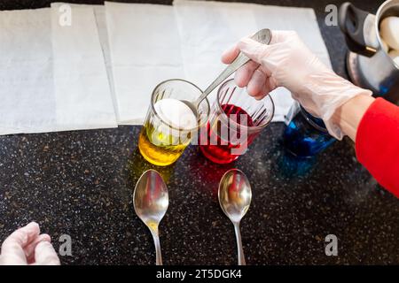 A woman dyes chicken eggs in multi-colored food dyes. Preparing for the feast of the holy Easter. Stock Photo