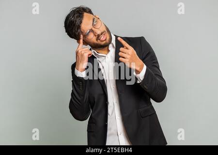 Need to think. Doubting pensive Indian businessman pondering, imagining in mind, wondering difficult solution, feeling confused, not sure about choice. Male Arabian man man isolated on gray background Stock Photo