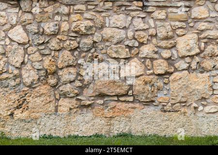 Old stone wall background texture. The building exterior is made of different sized rocks and cement in between. Natural material was used. Stock Photo