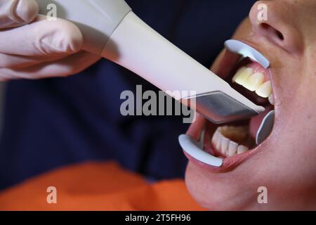 Dental office. Panoramic 3D dental scan. The dentist's workplace. Young woman visiting dentist at clinic. Male dentist with patient in clinic. Stock Photo