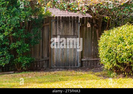 Wooden gate door in the garden surrounded by green trees and bushes Stock Photo