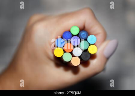 Colored chalks clamped to a fist on a gray background. Shallow depth of field Stock Photo