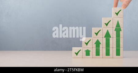 Wooden blocks checklist and green check mark icons with hand on table background. Goals achievement and business success. Task completion. checklist o Stock Photo