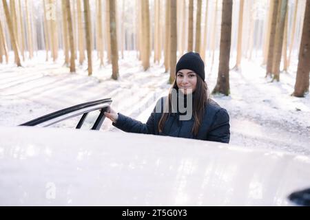 Photo of woman opens the door of the car in snowy forest. Preparing for skiing Stock Photo