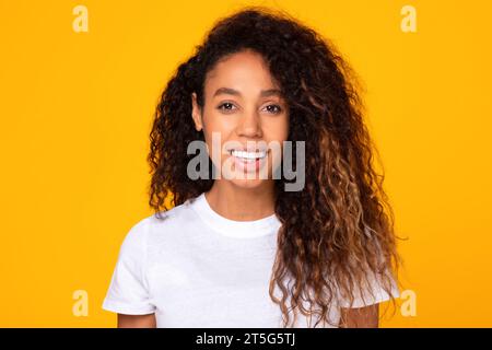 Portrait of happy black young lady with curly hair, studio Stock Photo