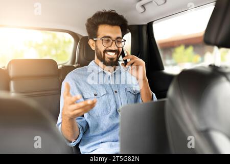 Positive indian businessman working online, going to airport by taxi Stock Photo